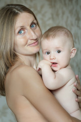 Indoor family portrait of cheerful mother with her baby child