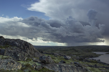 Majestic stormy cloud and sun beams over a lake in the mountains. Arctic summer, the tundra, Norway.