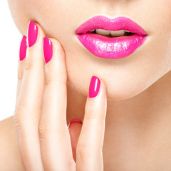 Obraz premium Closeup woman hand with pink nails near lips.