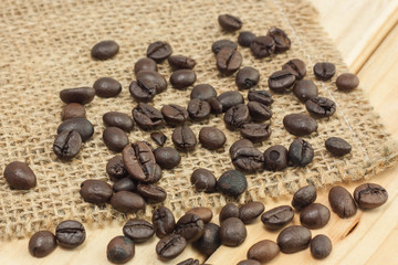 Coffee beans on sackcloth and wood background.