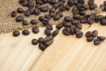 Coffee beans on sackcloth and wood background.