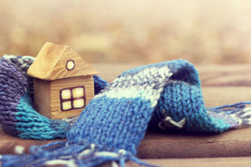  property insurance/ small wooden house in a warm blue scarf  - obrazy, fototapety, plakaty