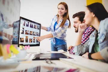 Fototapeta premium Smiling businesswoman showing computer screen to coworkers 