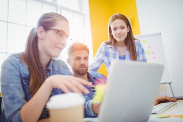 Creative business people looking at laptop