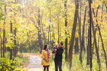 Fototapeta premium Happy young family walking down the road outside in autumn nature.