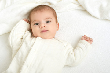 baby portrait lie on white towel in bed, yellow toned