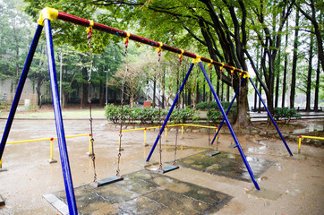 雨の公園の雨に濡れたブランコ