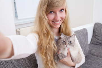 young woman taking selfie of ragdoll cat and her