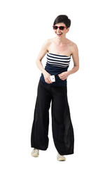 Young stylish woman wearing sunglasses laughing while holding mobile phone. Full body length portrait isolated over white studio background.