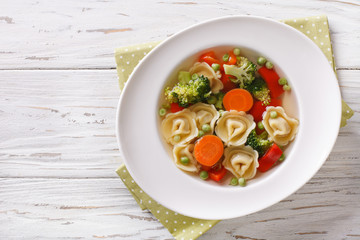 Vegetable soup with tortellini close-up. horizontal top view