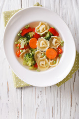 Vegetable soup with tortellini close-up. vertical top view