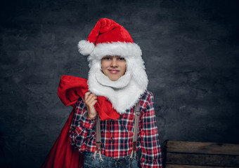 A boy in Santa's hat holds New Year gift sack.