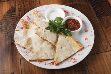 quesadilla with beef and chicken on brown wood table. quesadilla and sauce.