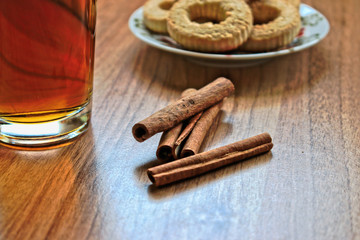 A cup of tea and biscuits with cinnamon on a wooden table