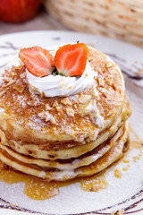 stack of homemade pancake with maple syrup and strawberry toppin