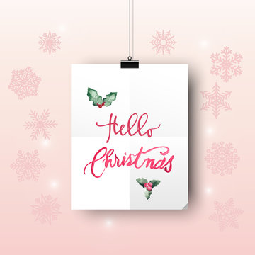 Hello Christmas a hanging clip white paper with pink text and Christmas leave on light pink gradient background and snowflakes.