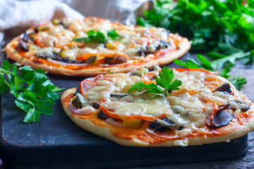 Home made fresh italian pizza with vegetable. Served on black stone surface.
