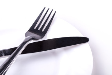 Knife and fork on empty dish on a white