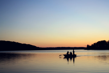 Naklejka na ściany i meble Evening fishing at the lake. Boat with fishermen.