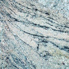 Wall of granite with stone layers of different colors. Texture. Toned photo. Close up architecture photography.