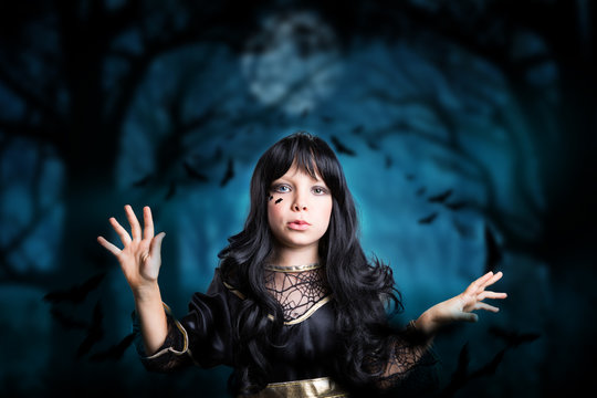 kleines Mädchen als Hexe verkleidet, im Wald mit vielen Fledermäusen 