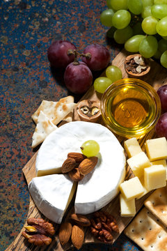 snacks and camembert on dark background, top view vertical