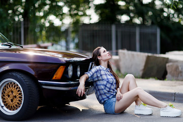 Young woman sitting on the ground next to car
