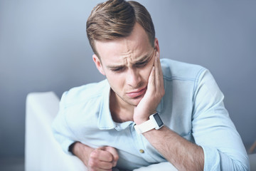 Handsome unhappy man suffering from toothache.