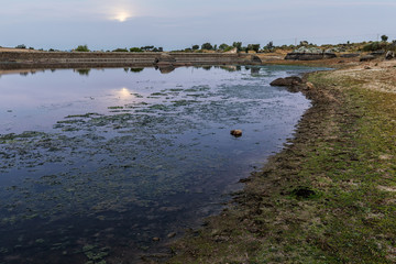 Sunrise in the Natural Area of Barruecos.  In the background the moonlight through the clouds. Extremadura. Spain.