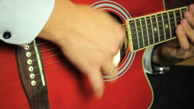 Guitarist playing on six-string acoustic guitar. Close up of hands and guitar strings.