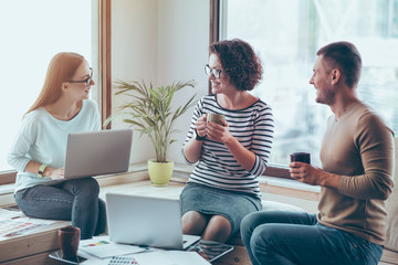 Cheerful colleagues drinking coffee in the office