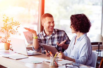 Positive  smiling colleagues talking at the table