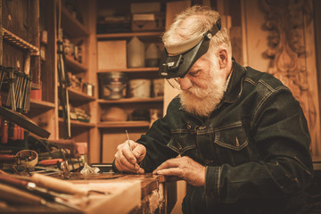 Senior restorer working with antique decor element in his workshop