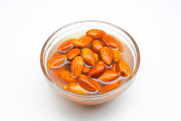 Raw almonds soaking in a white bowl of water