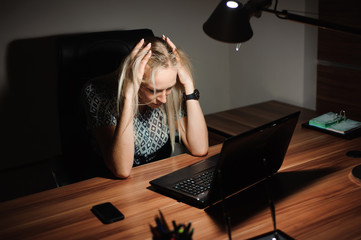 Portrait of stressed businesswoman sitting at office desk and th