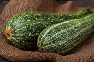 green zucchini on sackcloth and wooden background