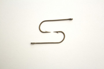 Two fishing hooks on a white paper background