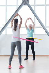 Positive confident women using hula hoops for training