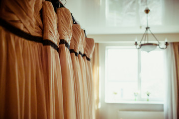 White day light illuminates beige dresses hanging on the wardrob