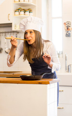 Adorable woman cooking in the kithcen and tasting the food