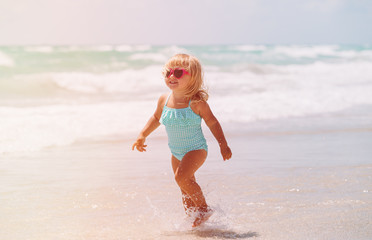 little girl run play with waves on the beach