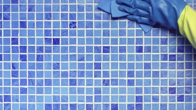 Wipe blue swimming pool wall tile with sponge cloth