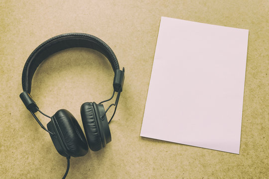 Headphone with white paper note on wood desk in music studio. (Warm tone)