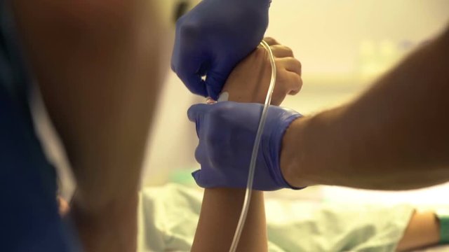 Before giving birth, a nurse is giving an injection into the woman's hand. Close-up shot.
