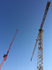 Two building cranes on blue sky