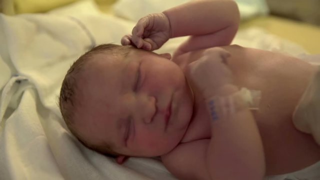 A nurse is putting a diaper on a new born baby. A baby is crying a lot. Close-up shot.
