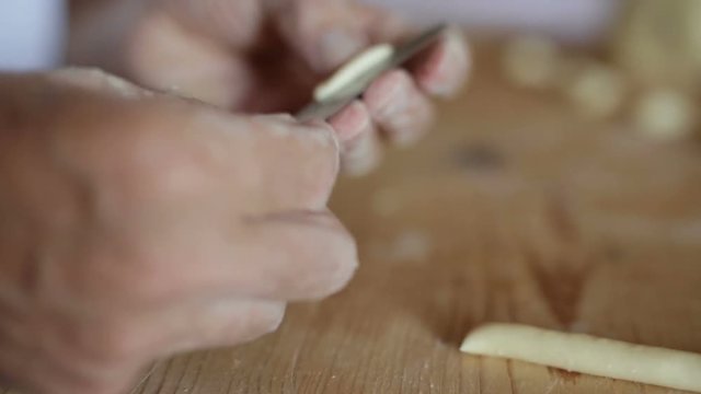 Uomo mezza et&agrave; che sta facendo la pasta fatta in casa su un tagliere di legno.