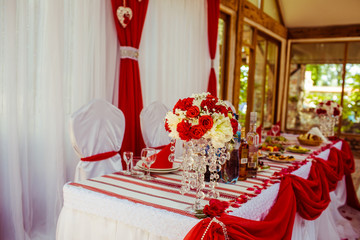 White dinner table decorated with red cloth and bouquets