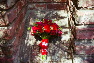 Gorgeous red bouquet lies on the brick wall