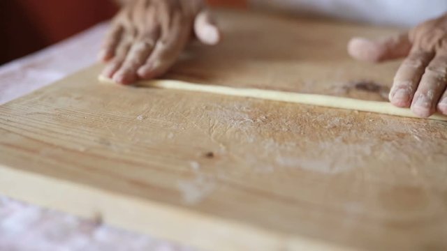 Uomo mezza et&agrave; che sta facendo la pasta fatta in casa su un tagliere di legno.